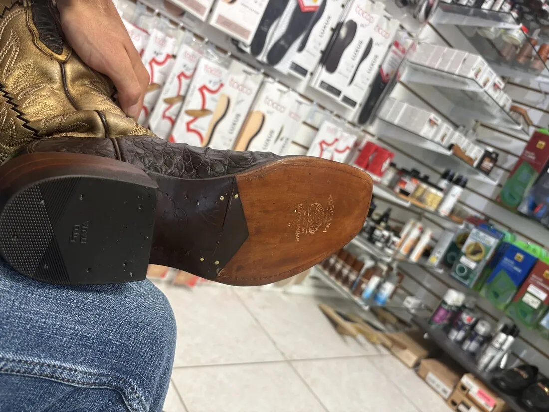 A cowboy boot with a new leather sole and heel, held up in the Magic Shoe shop