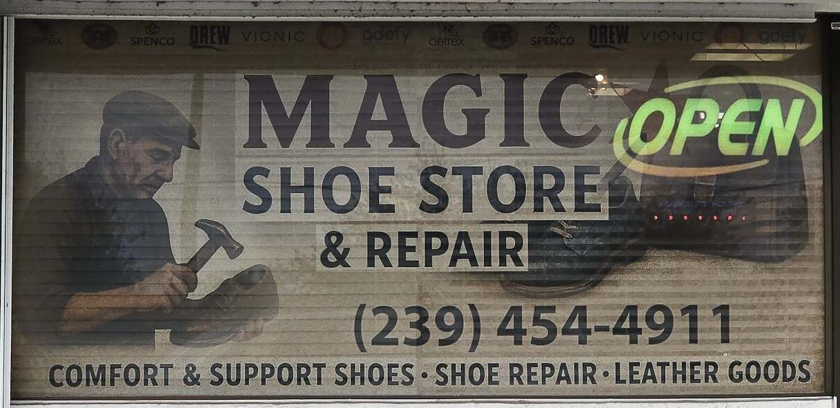The Magic Shoe Store & Repair window sign in Kapok Plaza, Fort Myers, with the OPEN sign lit